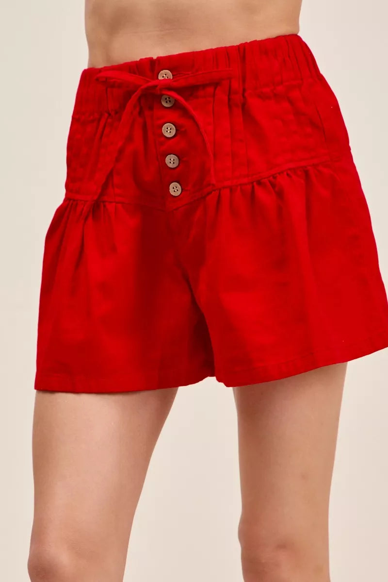 Red shorts with button details on a beige background
