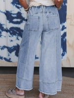 Light blue wide-leg jeans worn by a person against a tie-dye background