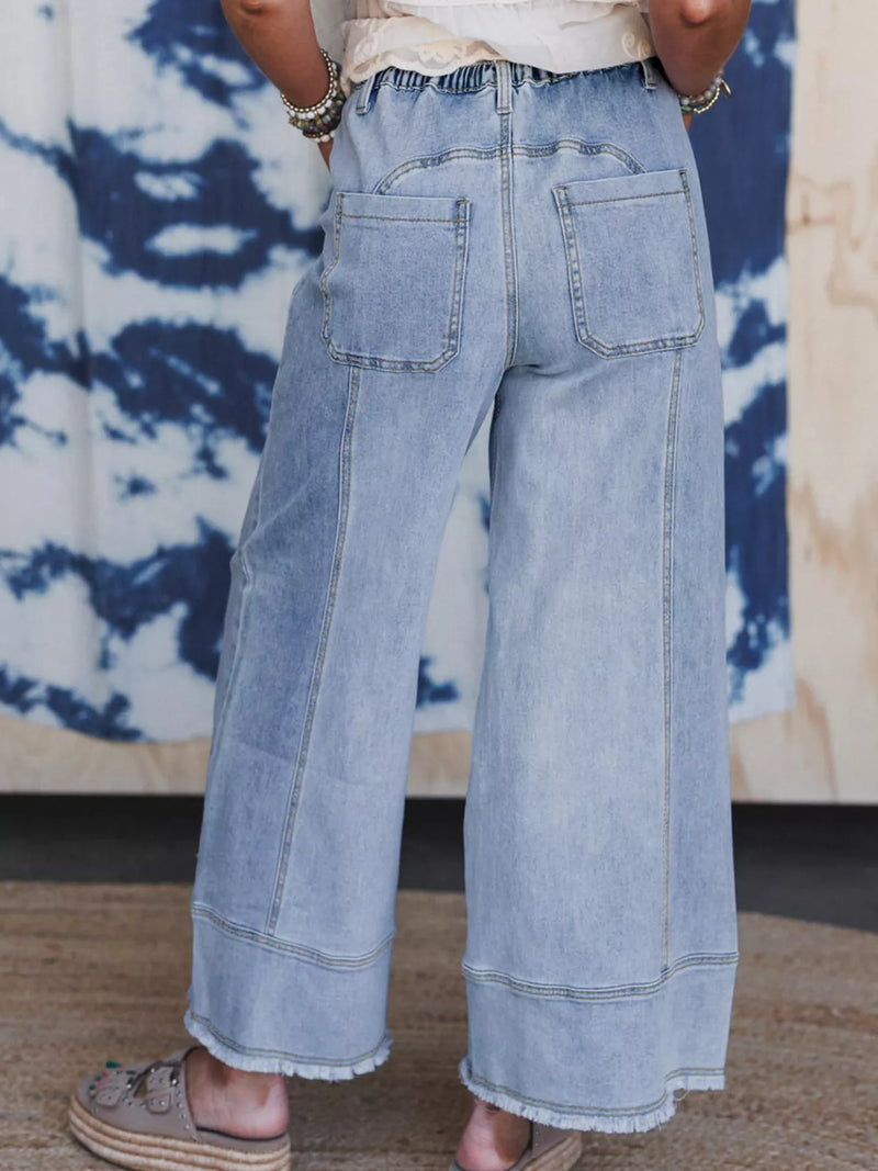 Light blue wide-leg jeans worn by a person against a tie-dye background