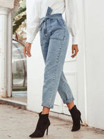 Person wearing light blue jeans and black ankle boots in an outdoor setting.