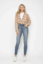 Woman wearing a plaid shirt and blue jeans against a white background