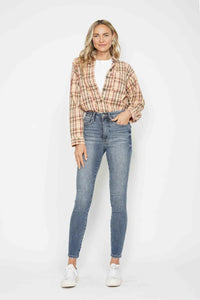 Woman wearing a plaid shirt and blue jeans against a white background