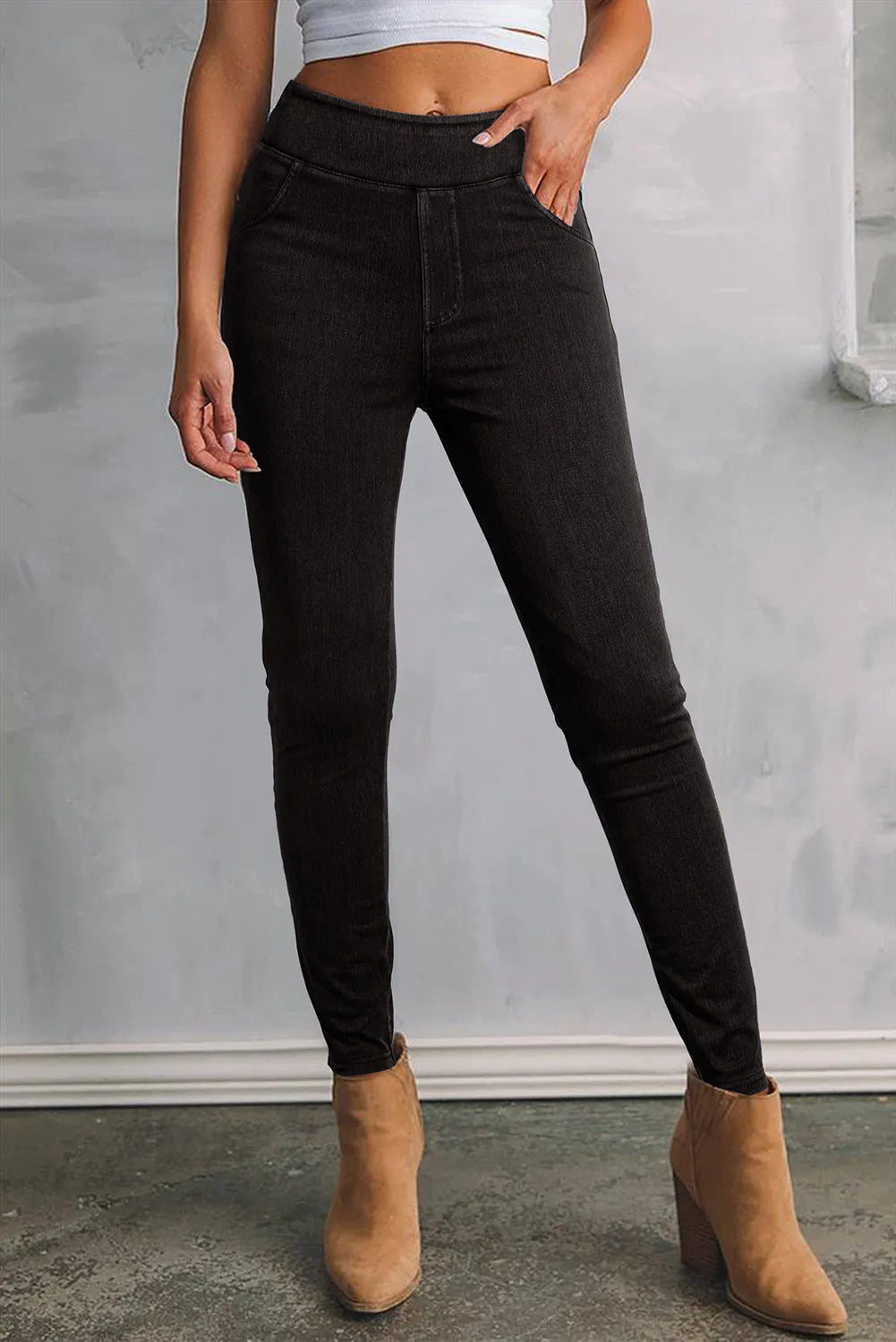 Person wearing black jeans and tan boots against a gray background