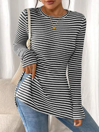 Person wearing a black and white striped sweater with blue jeans against a neutral background