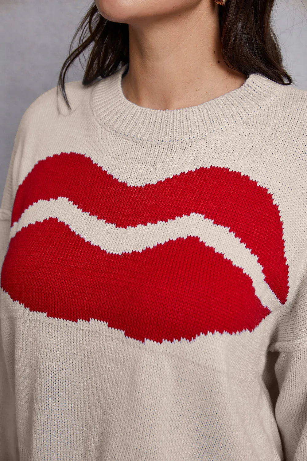 Beige sweater with red and white lip design worn by a person