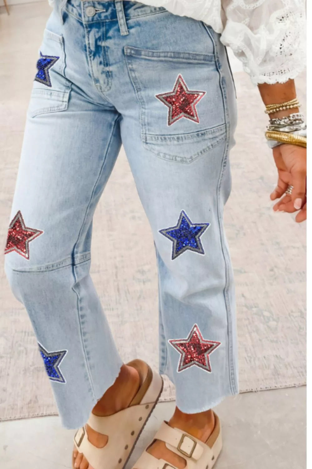 Light blue jeans with star patches worn by a person on a light background
