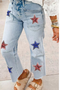 Light blue jeans with star patches worn by a person on a light background