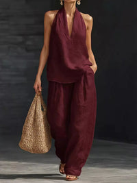 Woman in burgundy outfit holding a woven bag against a dark background