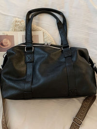 Black leather duffel bag on a textured surface