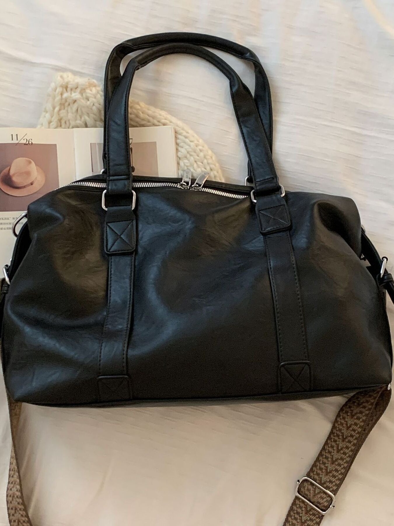 Black leather duffel bag on a textured surface