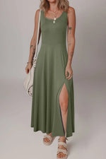 Woman wearing a green dress with a slit on a plain background