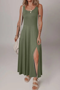 Woman wearing a green dress with a slit on a plain background