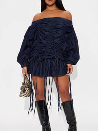 Navy off-shoulder dress with fringes and black knee-high boots on a white background