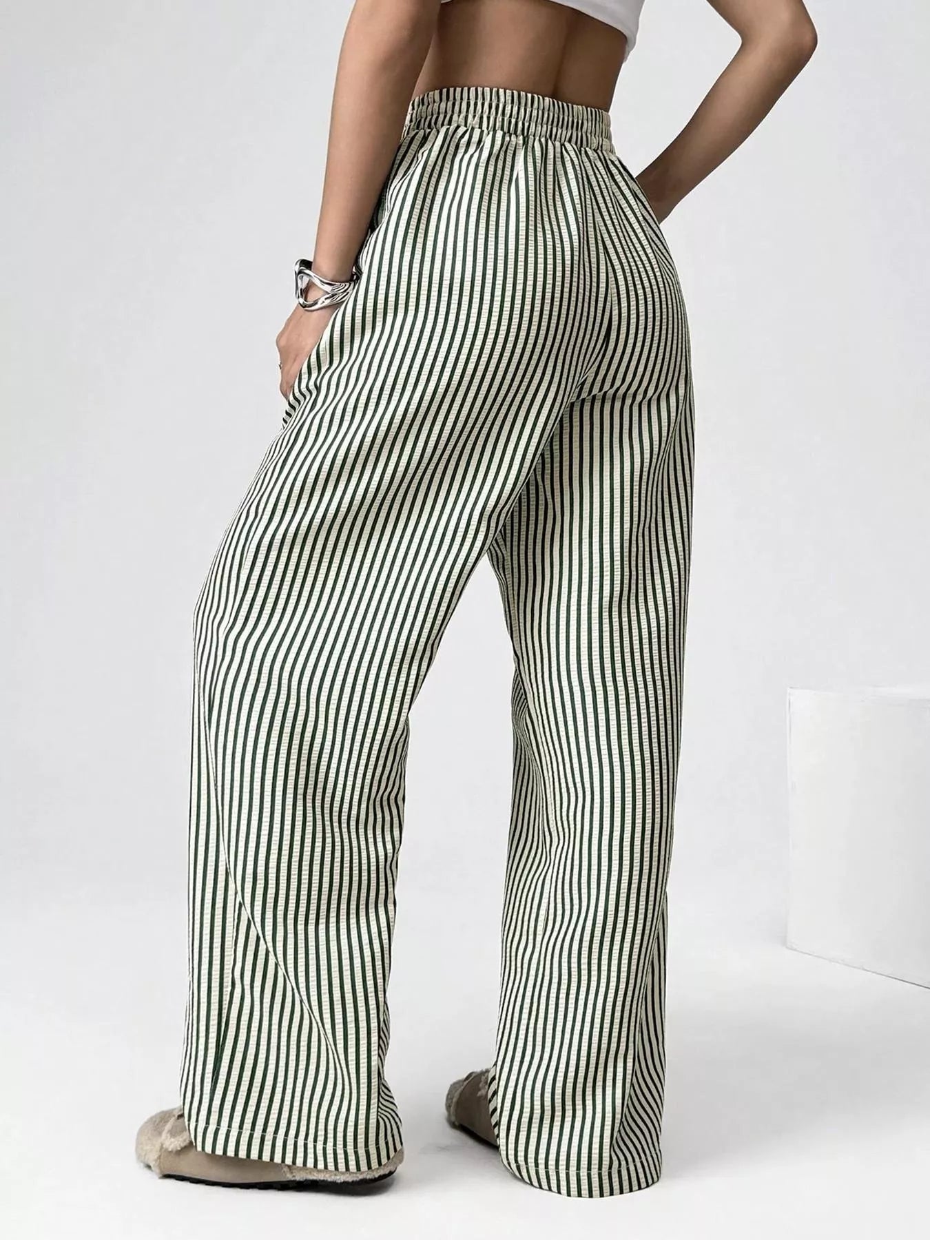 Person wearing green and white striped pants on a white background