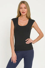 Woman wearing a black sleeveless top and blue pants on a white background