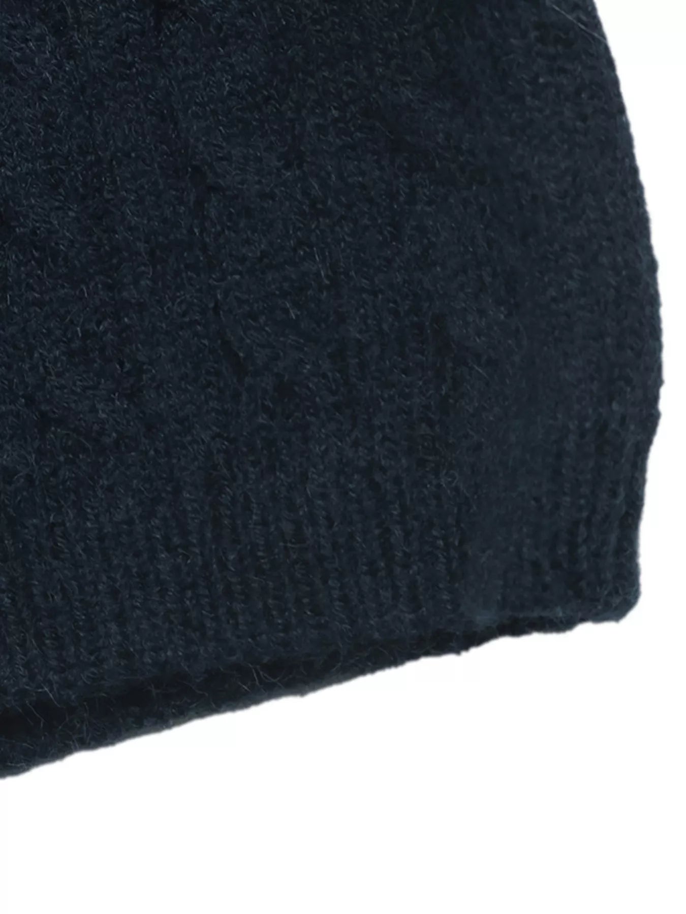 Close-up of a dark navy blue knit fabric, showing a textured cable-knit pattern and ribbed edge against a white background.