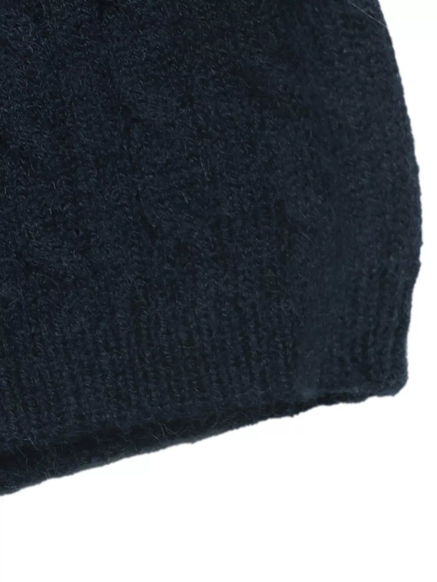 Close-up of a dark navy blue knit fabric, showing a textured cable-knit pattern and ribbed edge against a white background.