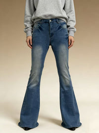 Person wearing blue flared jeans and a gray sweatshirt on a beige background