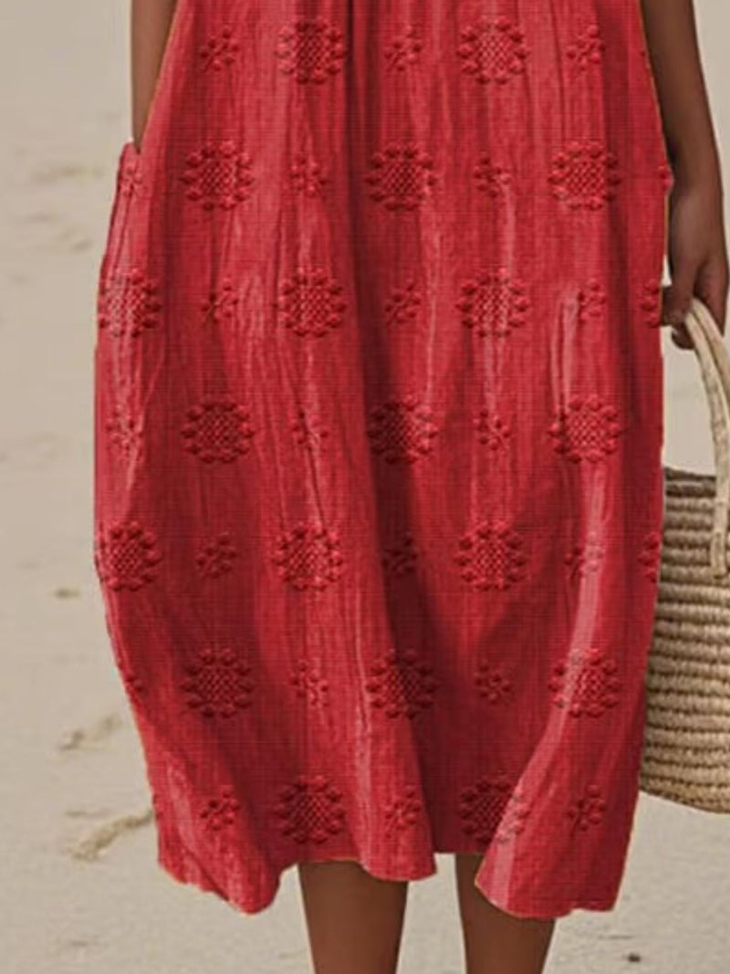 Red dress with textured pattern worn by a person on a beach.