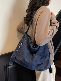 Person carrying a blue denim bag with a neutral background