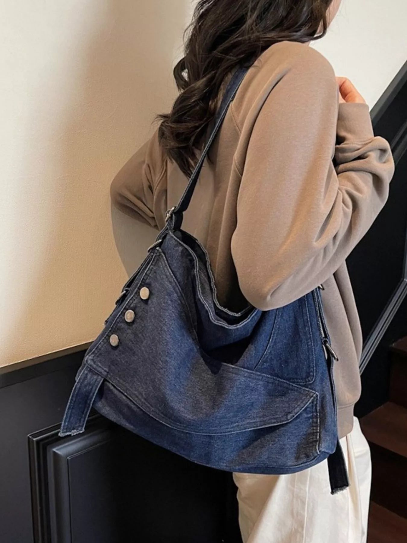 Person carrying a blue denim bag with a neutral background