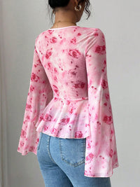 Person wearing a pink floral long-sleeve top and blue jeans against a plain background