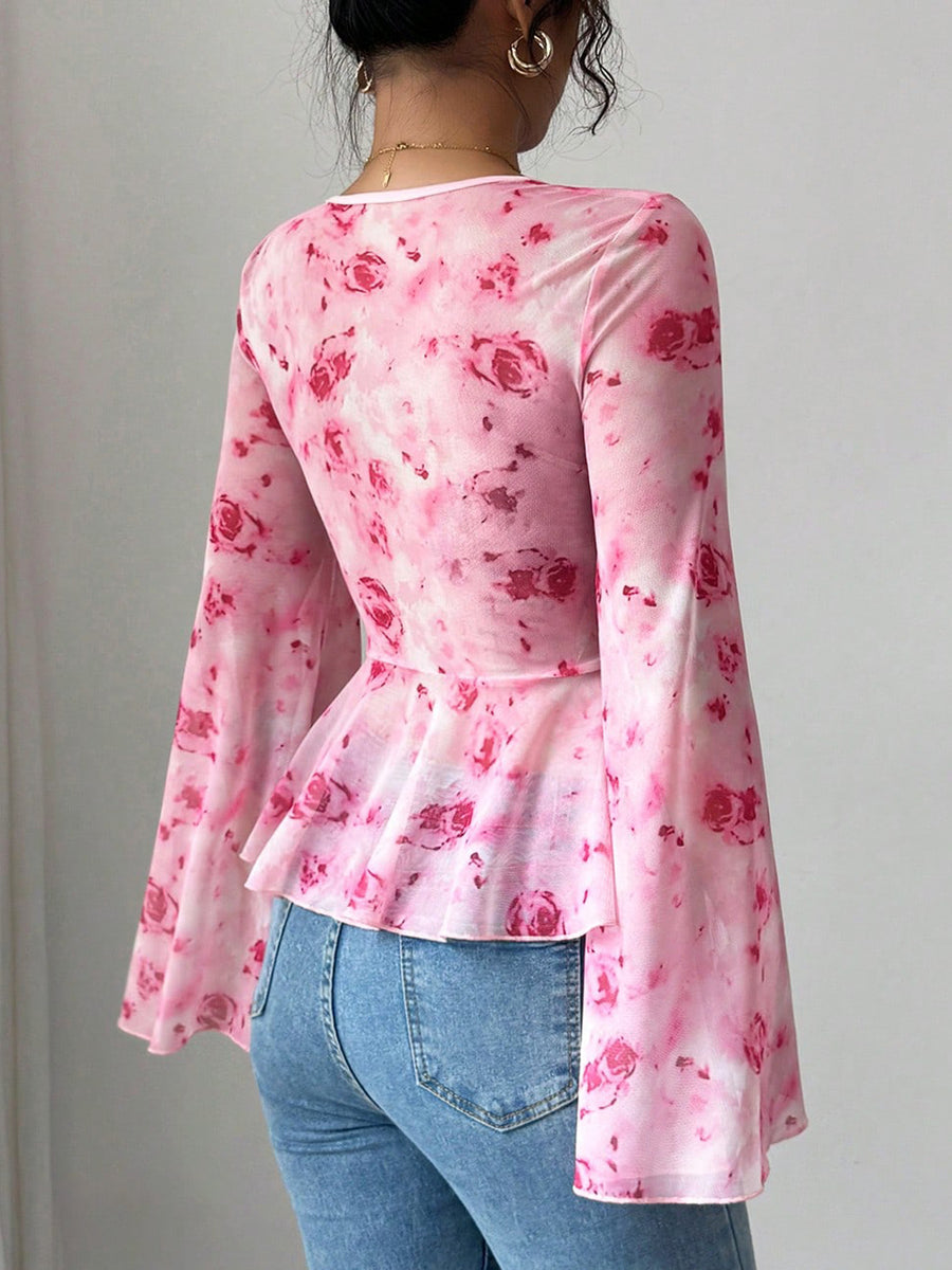 Person wearing a pink floral long-sleeve top and blue jeans against a plain background