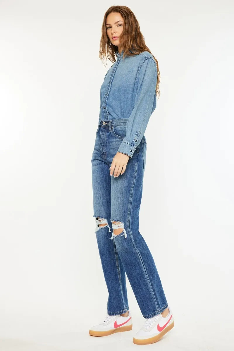 Woman wearing a denim outfit with ripped jeans on a white background