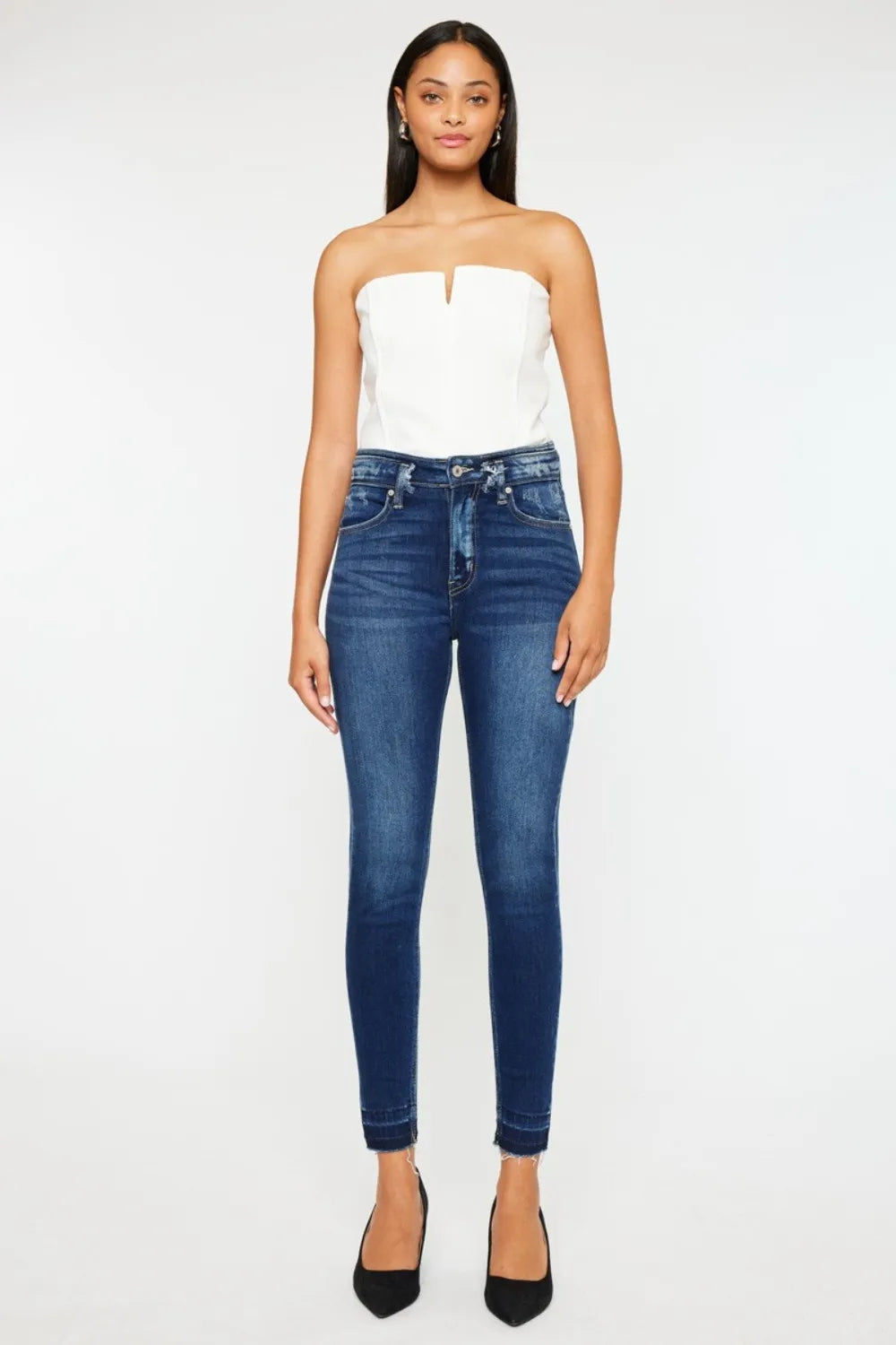 Woman wearing a white strapless top and blue jeans on a white background