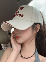 Person wearing a beige cap with red text inside a vehicle