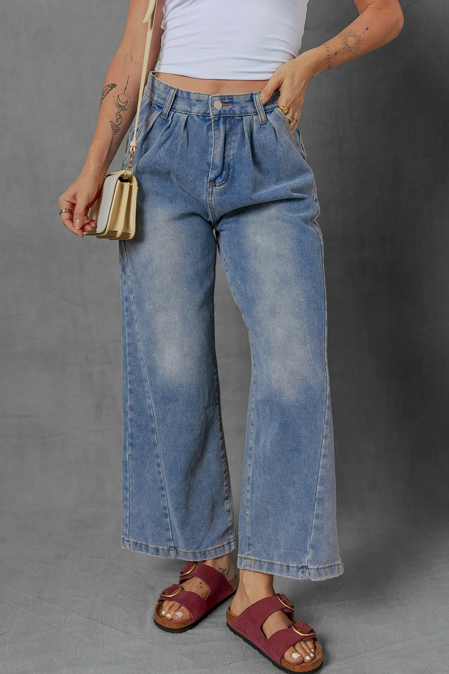 Person wearing blue jeans and a white top on a gray background
