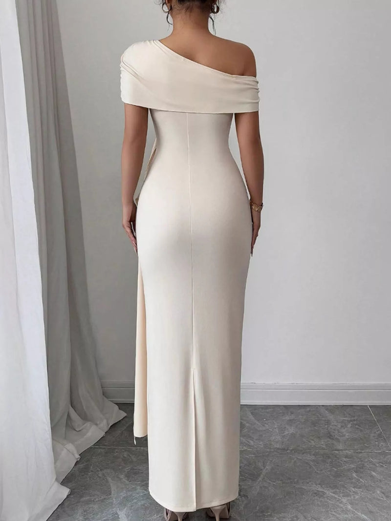 Woman wearing a one-shoulder white dress with a slit, standing against a plain background.