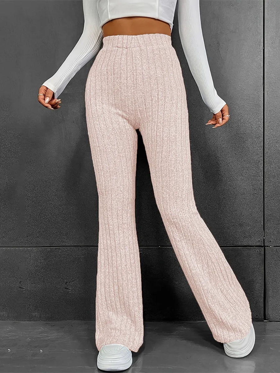 Person wearing light pink ribbed knit pants against a dark background