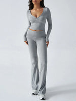 Woman wearing a gray long-sleeve top and high-waisted pants on a white background