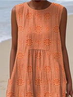 Person wearing an orange dress with floral patterns on a beach.