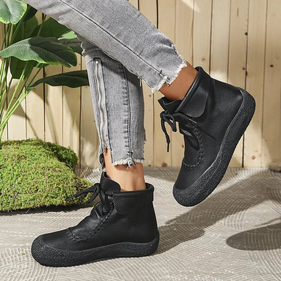 Person wearing black high-top sneakers with light gray jeans outdoors.