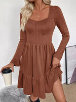 Woman wearing a brown ribbed dress holding a coffee cup indoors.