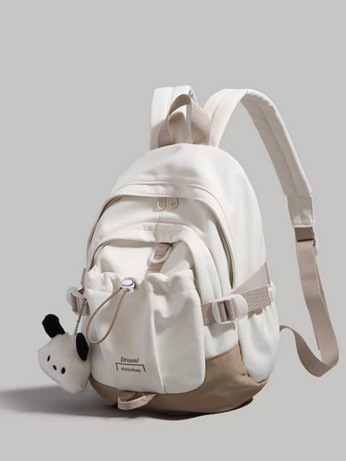 White backpack with a small panda plush toy on a gray background