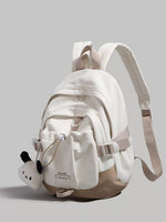 White backpack with a small panda plush toy on a gray background