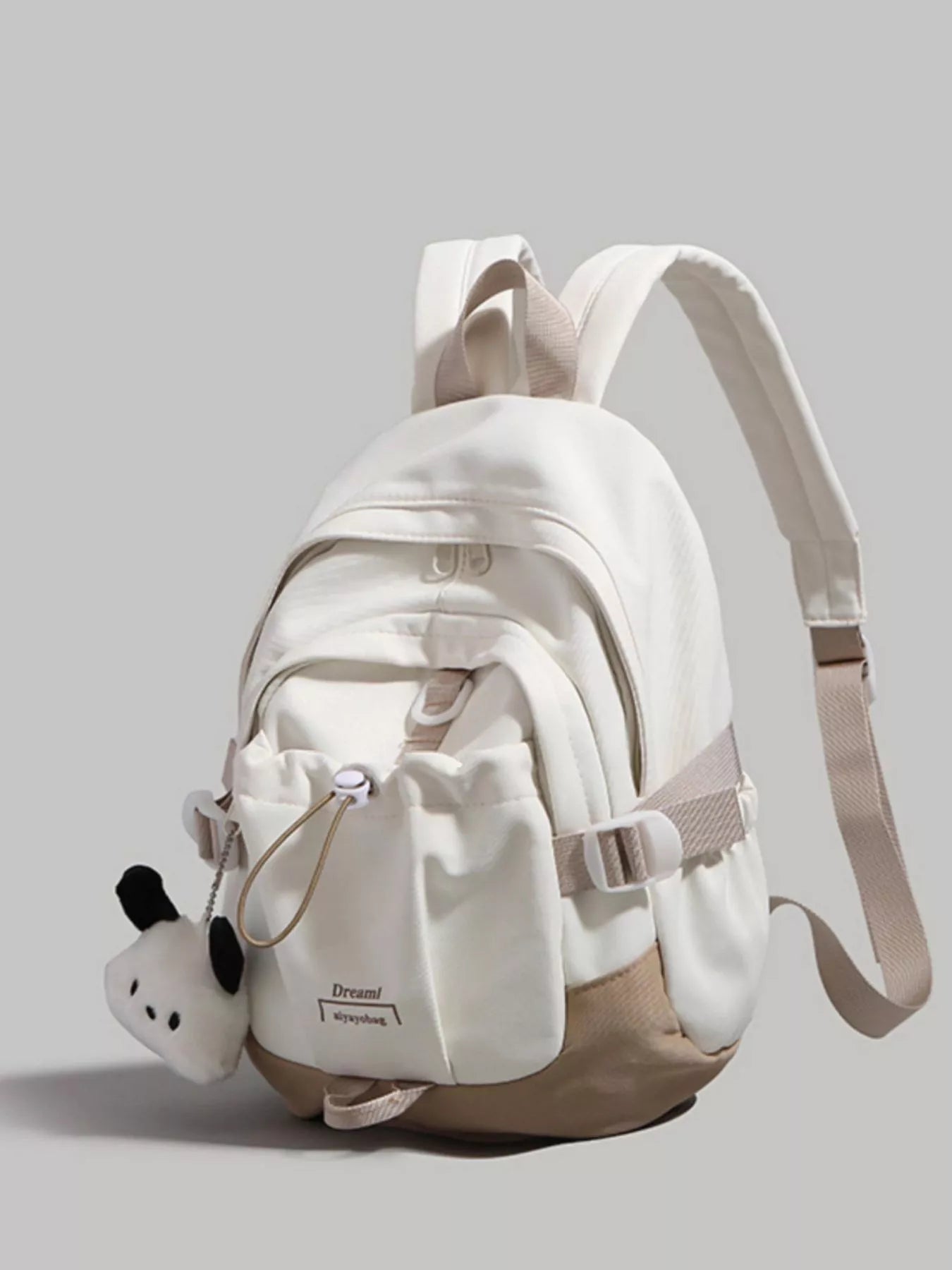White backpack with a small panda plush toy on a gray background