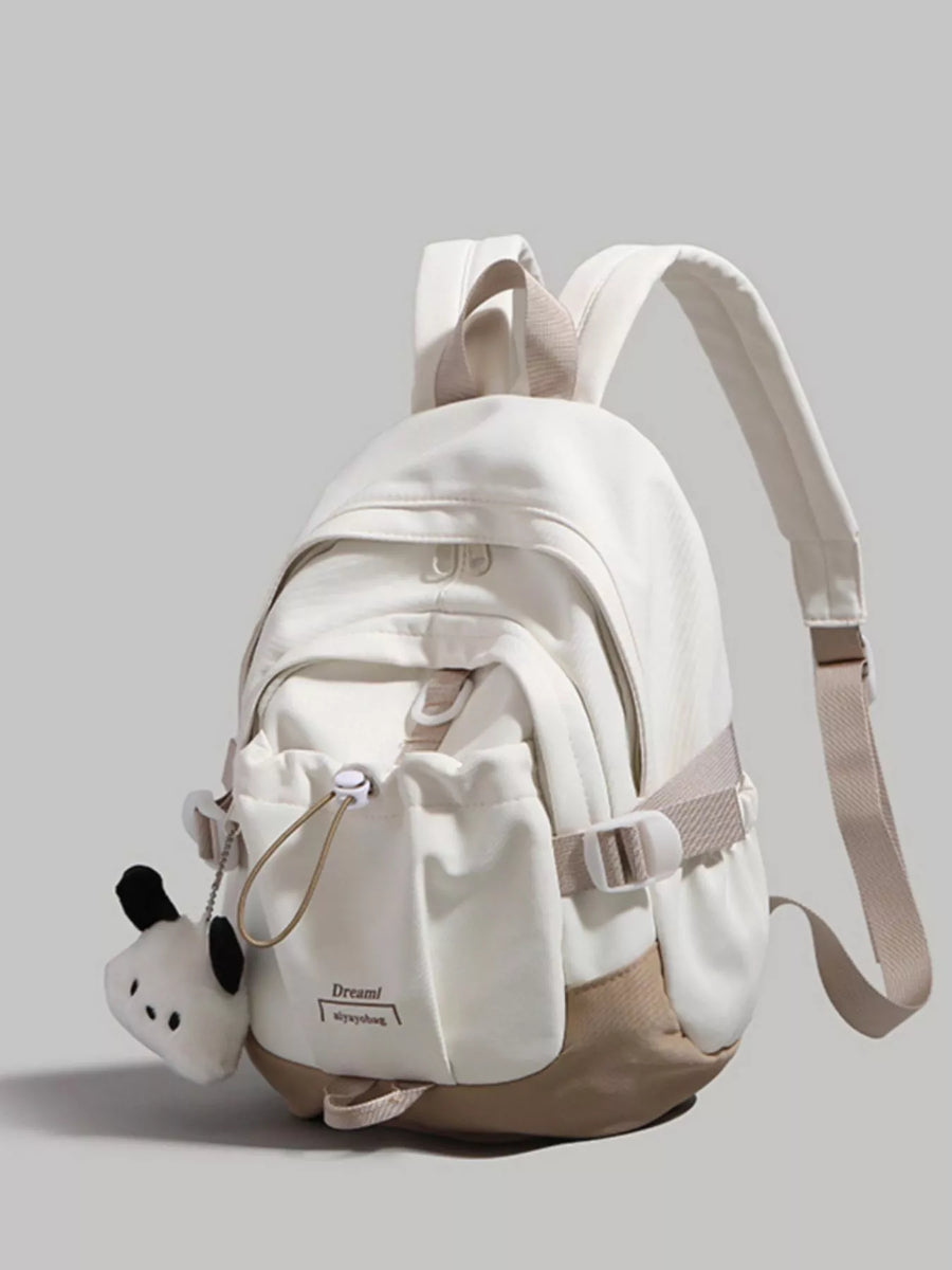 White backpack with a small panda plush toy on a gray background