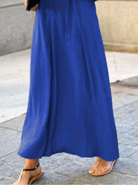Person wearing a long blue dress on a stone pavement.