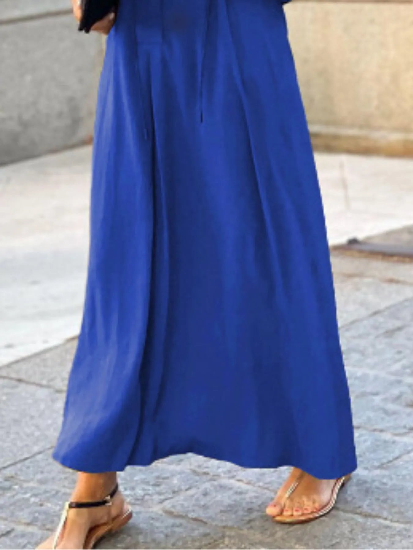 Person wearing a long blue dress on a stone pavement.