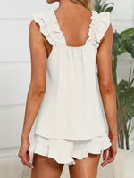 White ruffled top and shorts set worn by a person, with a blurred indoor background.