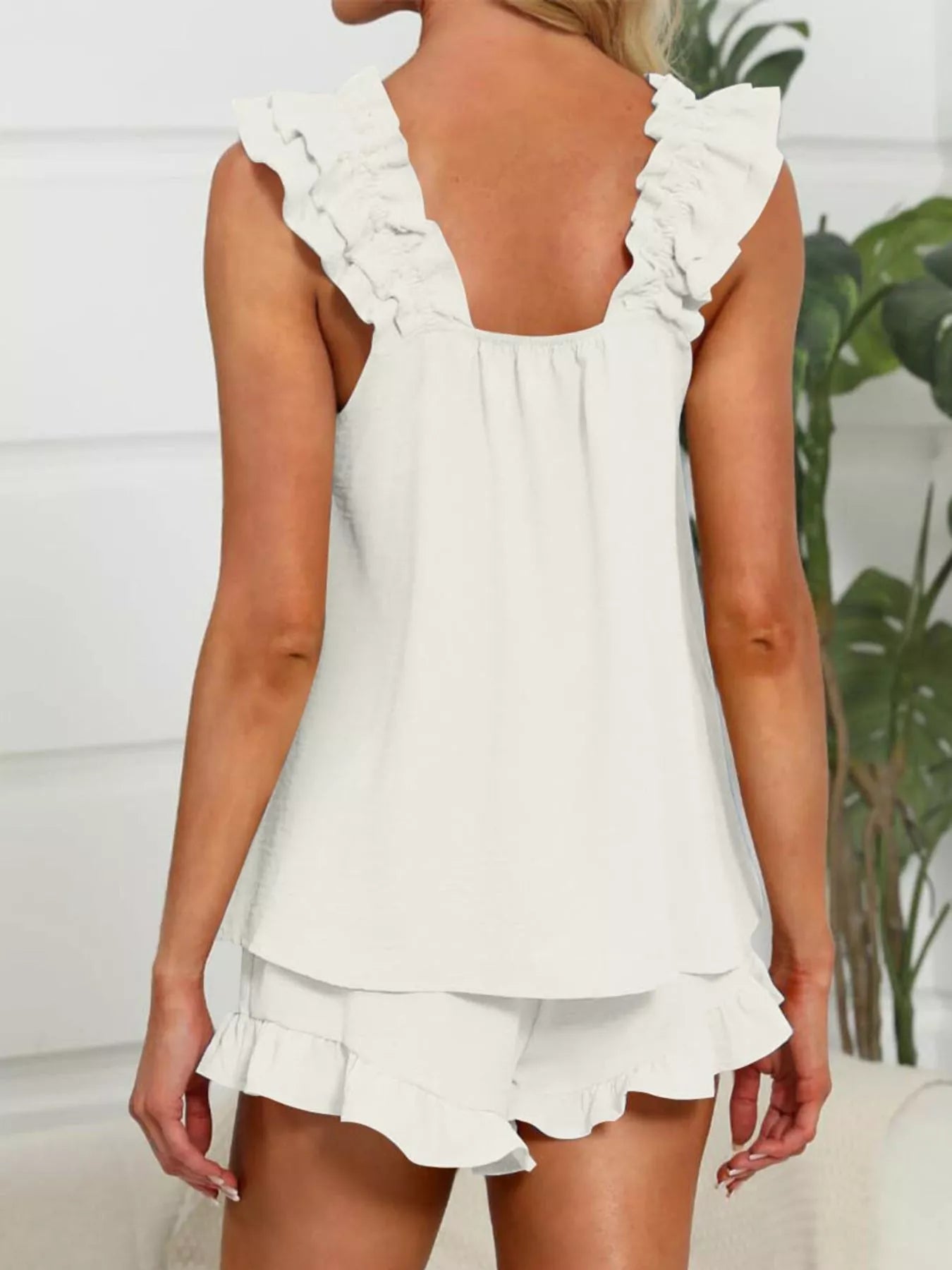White ruffled top and shorts set worn by a person, with a blurred indoor background.