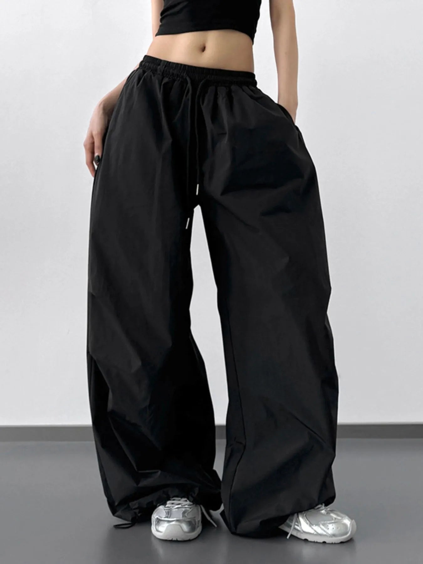 Person wearing black wide-leg pants and a black crop top on a plain background