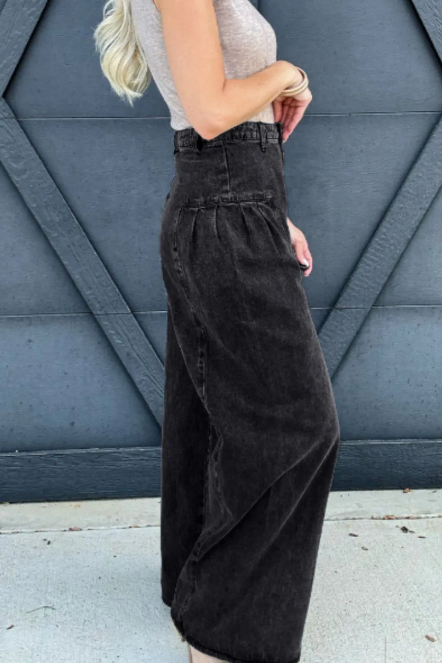 Person wearing black wide-leg pants against a blue wall.