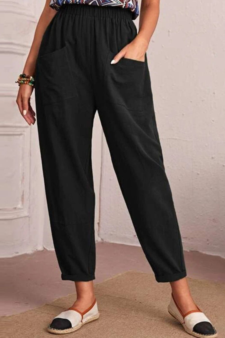 Person wearing black pants with a white brick wall background