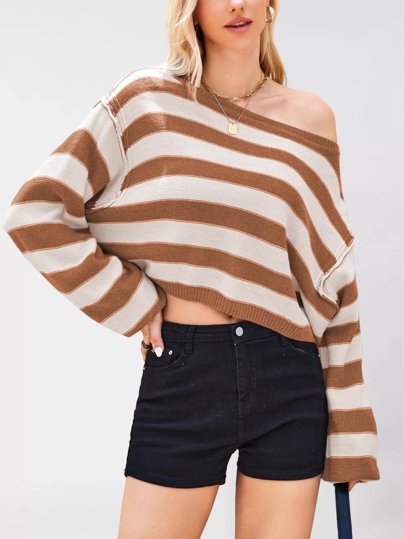 Person wearing a brown and beige striped sweater with black shorts on a white background