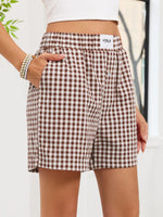 Person wearing brown and white checkered shorts with a visible brand logo.
